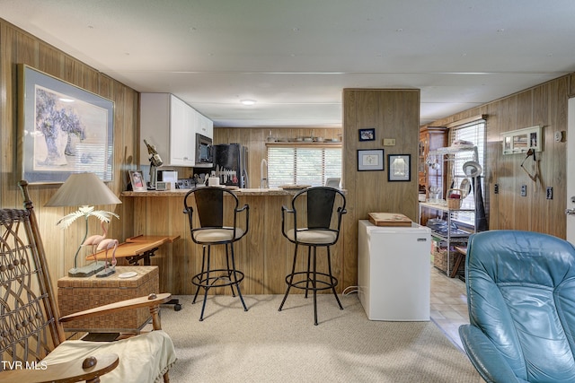 111 Jd Whitehead Rd, Roan Mountain, TN 37687 - kitchen with wooden walls, black microwave, freestanding refrigerator, light carpet, and healthy amount of natural light