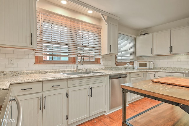 1449 Warpath Dr, Kingsport, TN 37664 - kitchen with a sink, stainless steel appliances, light wood-style flooring, decorative backsplash, and white cabinets