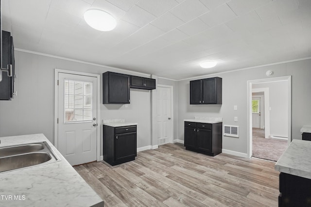 631 NE Meadow St, Coeburn, VA 24230 - kitchen with ornamental molding, light countertops, light wood-type flooring, a sink, and dark cabinets