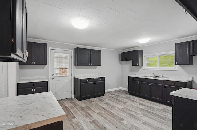 631 NE Meadow St, Coeburn, VA 24230 - kitchen with crown molding, light countertops, light wood finished floors, dark cabinetry, and a sink