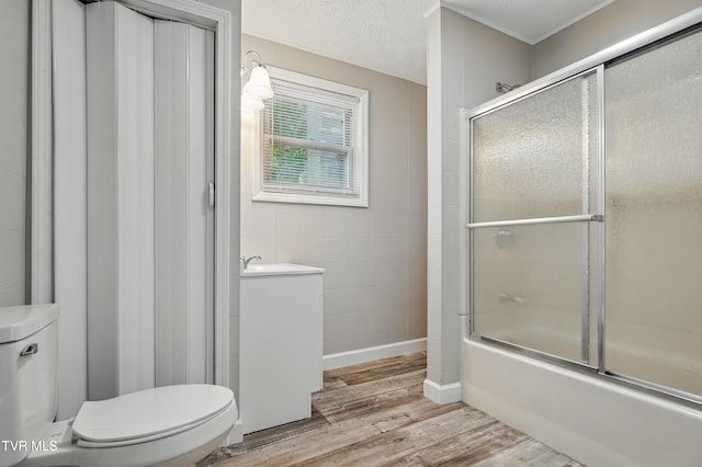 631 NE Meadow St, Coeburn, VA 24230 - full bathroom with toilet, wood finished floors, bath / shower combo with glass door, vanity, and tile walls