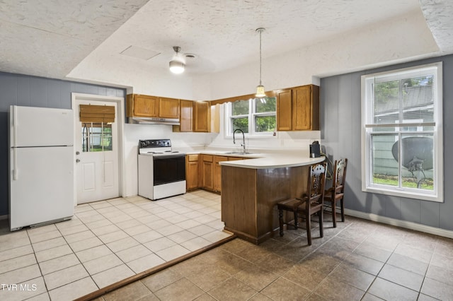 115 W Poplar St, Johnson City, TN 37604 - kitchen featuring white appliances, brown cabinets, a peninsula, light tile patterned floors, and pendant lighting