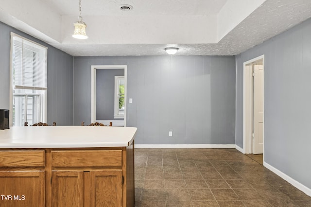 115 W Poplar St, Johnson City, TN 37604 - kitchen with a textured ceiling, brown cabinetry, a peninsula, light countertops, and decorative light fixtures