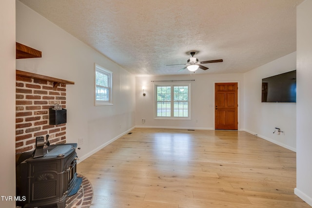 319 Woodland Rd, Jonesborough, TN 37659 - unfurnished living room with a wood stove, a ceiling fan, light wood finished floors, a textured ceiling, and baseboards