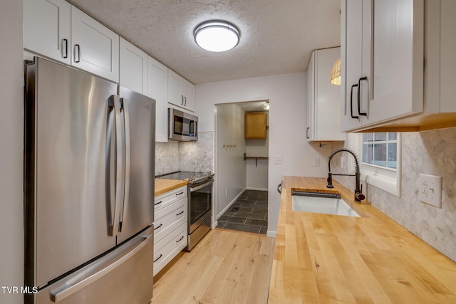 319 Woodland Rd, Jonesborough, TN 37659 - kitchen with stainless steel appliances, wooden counters, a sink, wood finished floors, and white cabinetry