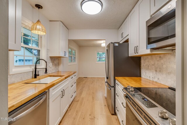 319 Woodland Rd, Jonesborough, TN 37659 - kitchen featuring butcher block countertops, appliances with stainless steel finishes, a sink, light wood-style flooring, and white cabinets