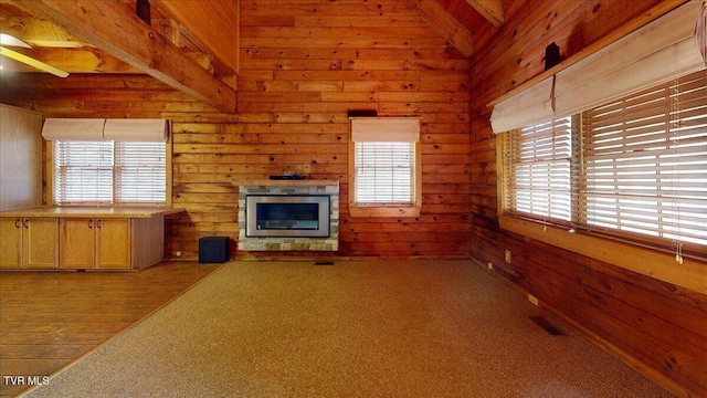 209 Brystone Dr, Gray, TN 37615 - unfurnished living room with healthy amount of natural light, wood walls, a glass covered fireplace, beam ceiling, and ceiling fan