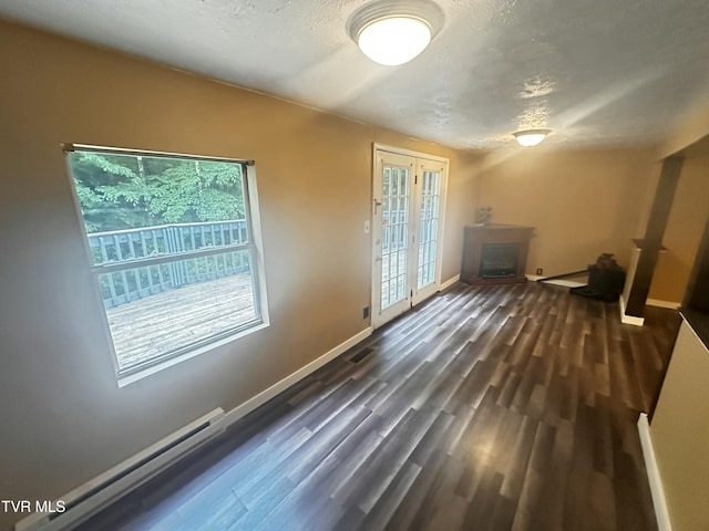 11510 Dogwood Ln, Pound, VA 24279 - empty room with a baseboard heating unit, a fireplace, baseboards, dark wood-type flooring, and a textured ceiling