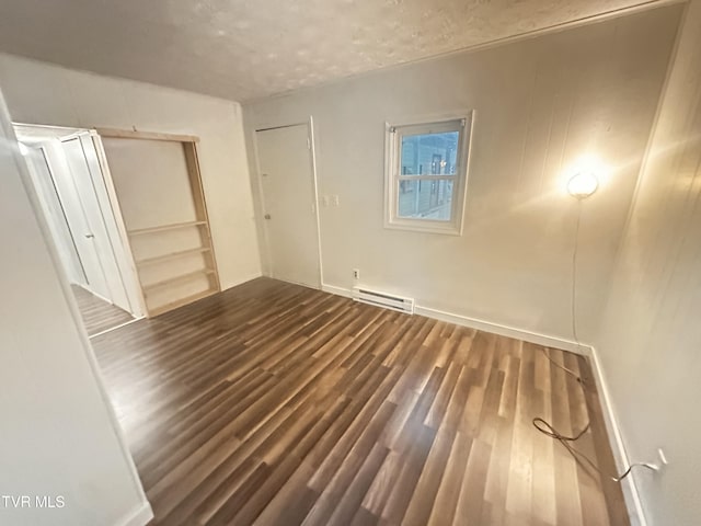 11510 Dogwood Ln, Pound, VA 24279 - unfurnished bedroom featuring a baseboard radiator, dark wood-type flooring, a textured ceiling, and a closet