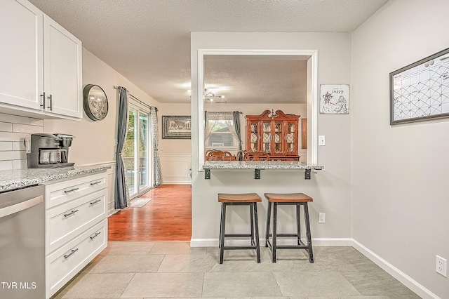 118 Greenmeadow Ln, Jonesborough, TN 37659 - kitchen featuring stainless steel dishwasher, a textured ceiling, white cabinets, a kitchen breakfast bar, and tasteful backsplash