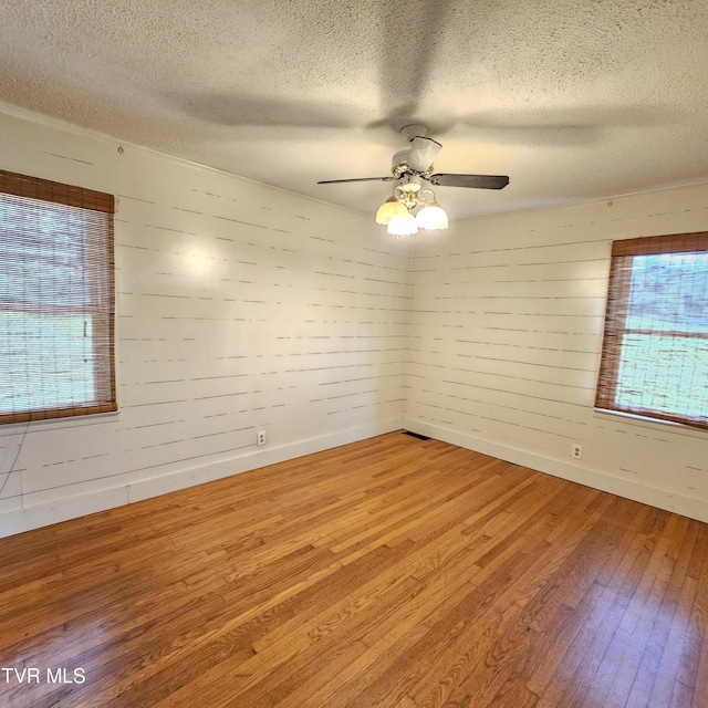 515 Chuckey Pike, Chuckey, TN 37641 - empty room with wood finished floors, healthy amount of natural light, a textured ceiling, wood walls, and ceiling fan