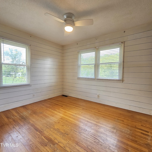 515 Chuckey Pike, Chuckey, TN 37641 - unfurnished room featuring light wood-style floors, a textured ceiling, wooden walls, and a ceiling fan