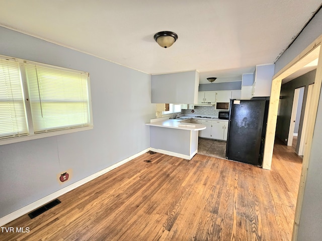 515 Chuckey Pike, Chuckey, TN 37641 - kitchen featuring black appliances, a peninsula, wood finished floors, light countertops, and backsplash