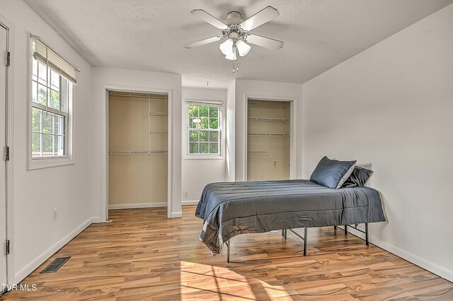 125 Cedar Valley Rd, Bristol, TN 37620 - bedroom with two closets, light wood-style floors, baseboards, ceiling fan, and a textured ceiling