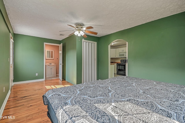 125 Cedar Valley Rd, Bristol, TN 37620 - bedroom with arched walkways, light wood-style floors, a textured ceiling, baseboards, and a ceiling fan