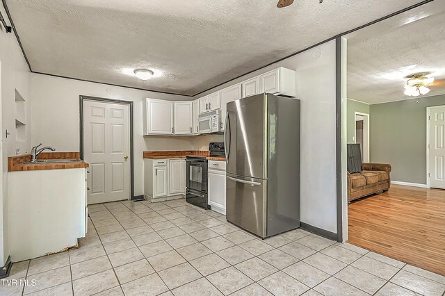 125 Cedar Valley Rd, Bristol, TN 37620 - kitchen featuring black range with electric stovetop, freestanding refrigerator, white microwave, a textured ceiling, and a sink
