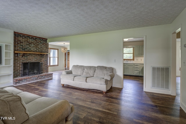 715 Powder Branch Rd, Elizabethton, TN 37643 - living room featuring dark wood-style flooring, healthy amount of natural light, a textured ceiling, a brick fireplace, and baseboards
