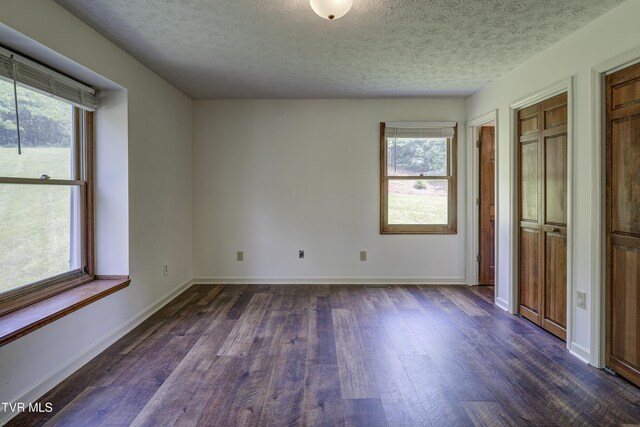715 Powder Branch Rd, Elizabethton, TN 37643 - unfurnished bedroom with dark wood finished floors, multiple windows, a textured ceiling, and baseboards