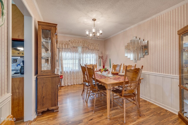 396 High Cir, Bristol, TN 37620 - dining space with wood finished floors, a chandelier, wallpapered walls, ornamental molding, and a textured ceiling