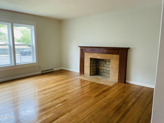 201 Brown St, Appalachia, VA 24216 - unfurnished living room featuring wood finished floors, a fireplace, baseboards, and a baseboard radiator