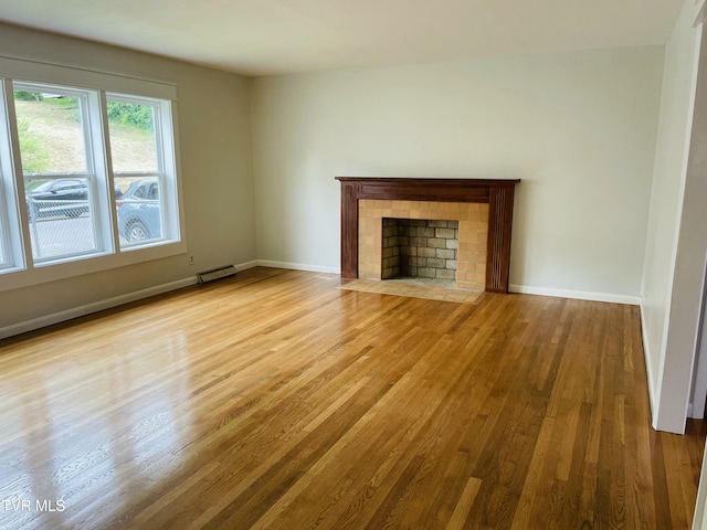 201 Brown St, Appalachia, VA 24216 - unfurnished living room with wood finished floors, a tile fireplace, a baseboard radiator, and baseboards