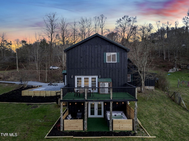 136 Beecher Holtsclaw Rd, Roan Mountain, TN 37687 - back of property at dusk featuring french doors, a deck, a yard, board and batten siding, and a patio