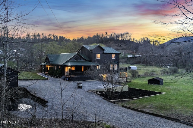 136 Beecher Holtsclaw Rd, Roan Mountain, TN 37687 - back of house at dusk featuring covered porch, a yard, and gravel driveway