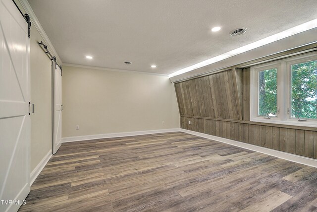 505 Red Oak Ln, Kingsport, TN 37663 - unfurnished room with a barn door, wood finished floors, ornamental molding, recessed lighting, and a textured ceiling