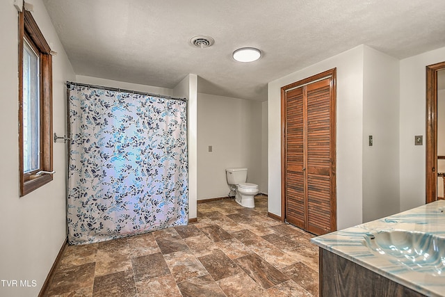 14191 King Mill Pike, Bristol, VA 24202 - bathroom with baseboards, toilet, a closet, stone finish flooring, and a textured ceiling