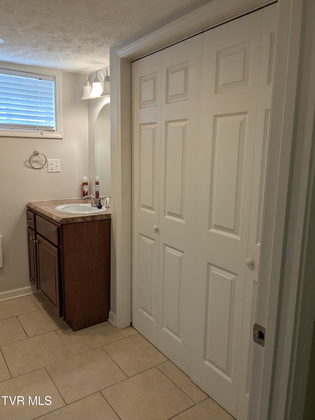 1319 5th St, Bristol, TN 37620 - bathroom featuring vanity, tile patterned flooring, a textured ceiling, baseboards, and a closet
