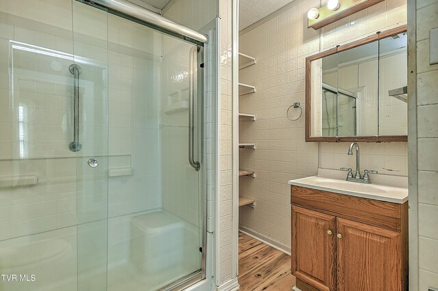 1725 Highland St, Kingsport, TN 37664 - full bathroom featuring wood finished floors, a shower stall, vanity, and tile walls