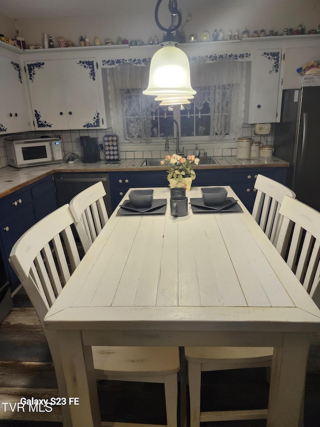 127 Banner St, Erwin, TN 37650 - kitchen with blue cabinetry, white microwave, decorative backsplash, and a sink