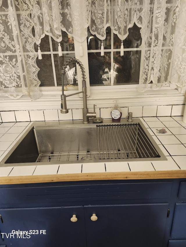127 Banner St, Erwin, TN 37650 - kitchen view of blue cabinets, a sink, and tasteful backsplash