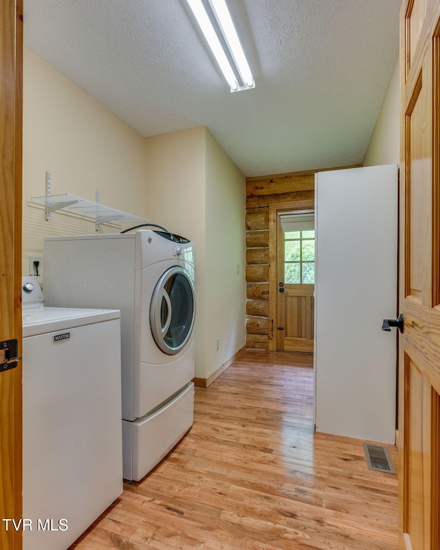 366 Judge Ben Allen Rd, Elizabethton, TN 37643 - laundry room featuring log walls, washing machine and clothes dryer, light wood finished floors, a textured ceiling, and baseboards