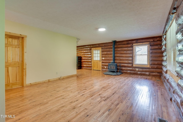 366 Judge Ben Allen Rd, Elizabethton, TN 37643 - unfurnished living room with a wood stove, wood-type flooring, rustic walls, baseboards, and a textured ceiling