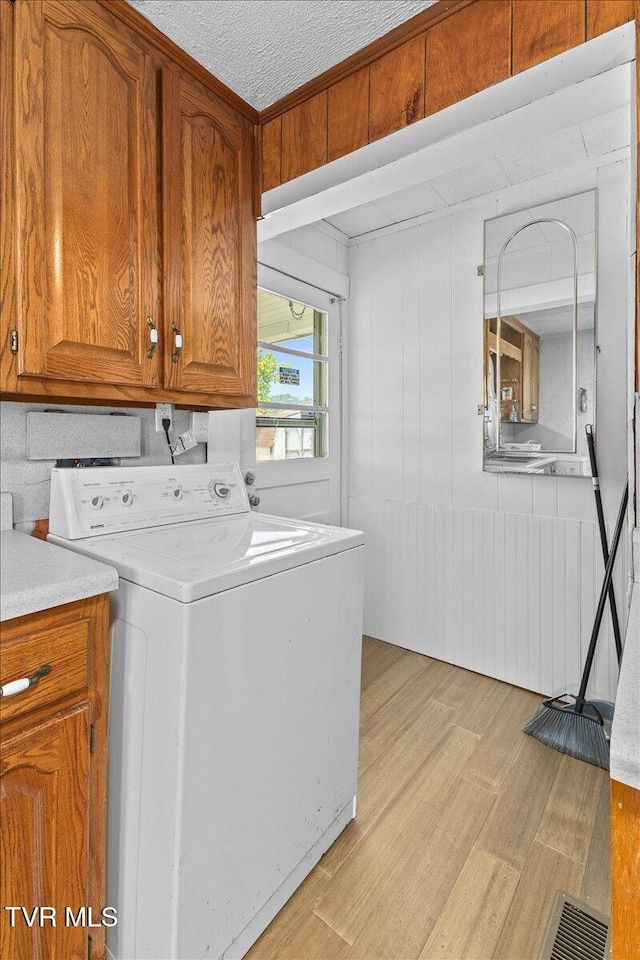 204 E Millpond St, Kingsport, TN 37660 - laundry room with washer / clothes dryer, cabinet space, light wood-style flooring, and a textured ceiling