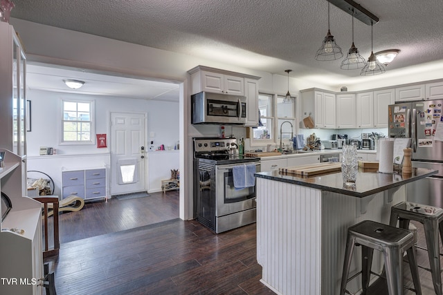 175 Shenandoah Dr, Johnson City, TN 37601 - kitchen featuring appliances with stainless steel finishes, a breakfast bar area, a textured ceiling, dark wood finished floors, and hanging light fixtures