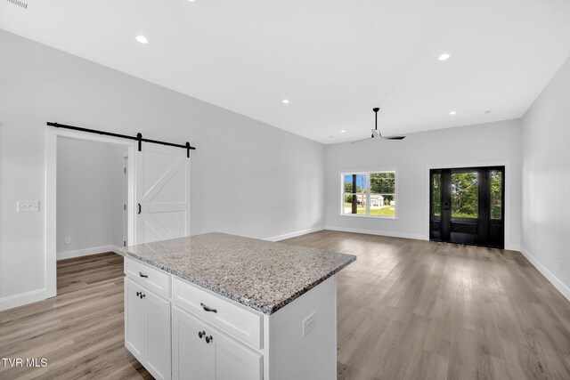 1930 Erwin Hwy, Greeneville, TN 37745 - kitchen featuring a barn door, light wood finished floors, a center island, white cabinetry, and light stone counters