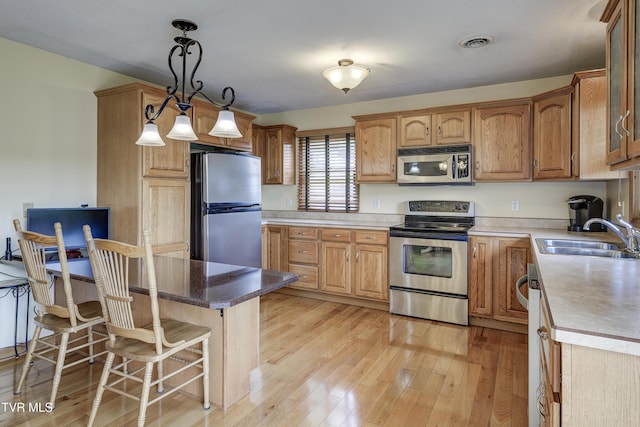 296 Redstone Dr, Bluff City, TN 37618 - kitchen featuring appliances with stainless steel finishes, a sink, a kitchen breakfast bar, light wood-type flooring, and hanging light fixtures