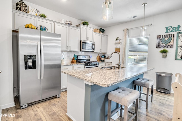 1058 Raccoon Ln, Piney Flats, TN 37686 - kitchen with appliances with stainless steel finishes, a sink, light wood-style flooring, backsplash, and a breakfast bar