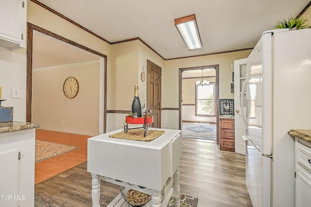 646 Meadow View Rd, Bristol, TN 37620 - kitchen with freestanding refrigerator, ornamental molding, wood finished floors, white cabinetry, and a chandelier