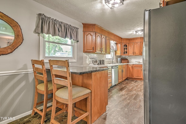 404 Stuffle St, Kingsport, TN 37660 - kitchen with appliances with stainless steel finishes, a textured ceiling, a wainscoted wall, a kitchen bar, and a peninsula