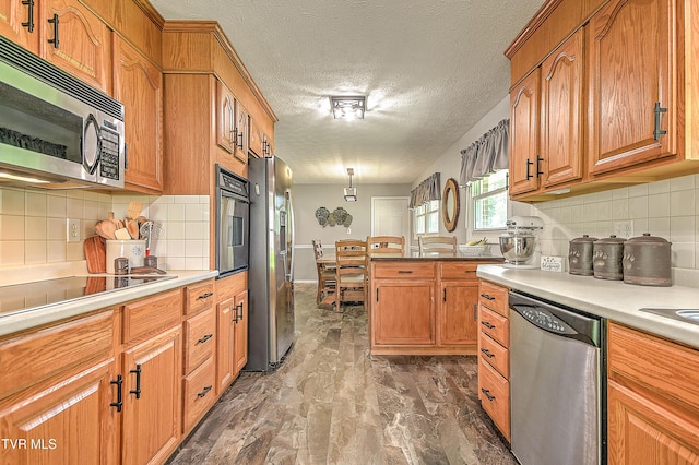 404 Stuffle St, Kingsport, TN 37660 - kitchen featuring appliances with stainless steel finishes, backsplash, brown cabinetry, light countertops, and a textured ceiling