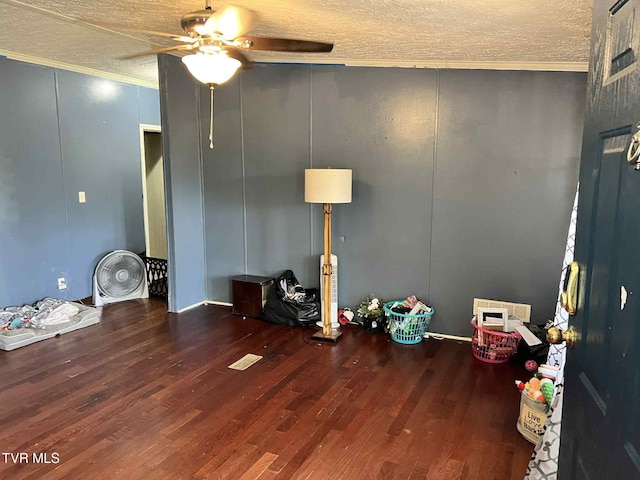 692 NE Hamner Ave, Norton, VA 24273 - unfurnished living room featuring ceiling fan, a decorative wall, a textured ceiling, wood finished floors, and crown molding