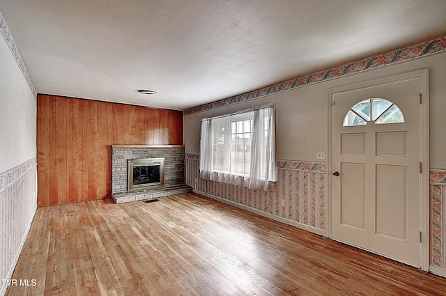 512 Old Airport Rd, Bristol, VA 24201 - unfurnished living room featuring light wood-style floors, wainscoting, a fireplace, and wood walls