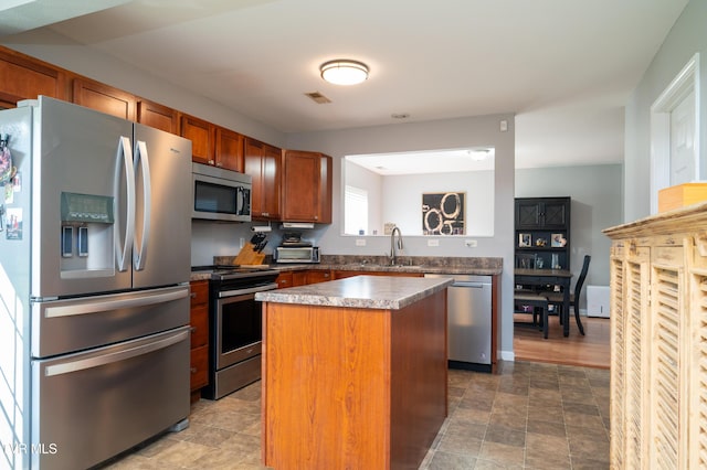395 Kings Rd, Piney Flats, TN 37686 - kitchen featuring stainless steel appliances, a center island, brown cabinetry, and stone finish floors