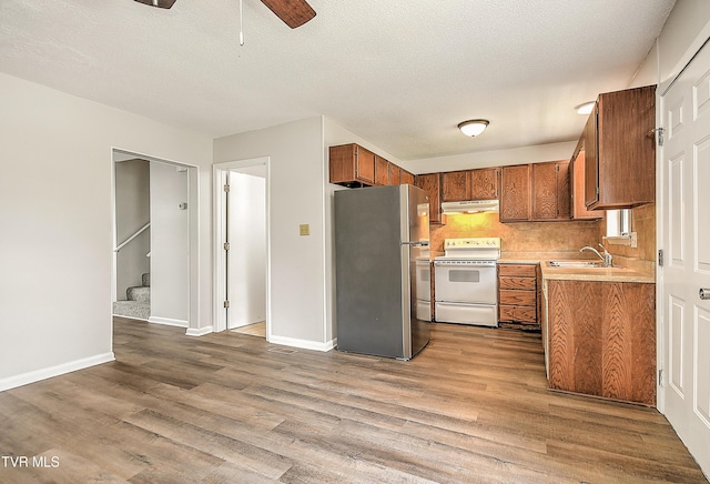 103 Northwinds Dr, Bristol, VA 24201 - kitchen featuring freestanding refrigerator, white electric stove, under cabinet range hood, brown cabinetry, and light countertops