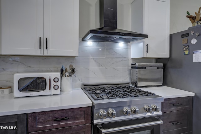 457 W St, Greeneville, TN 37745 - kitchen with wall chimney range hood, stainless steel stove, white microwave, tasteful backsplash, and white cabinetry