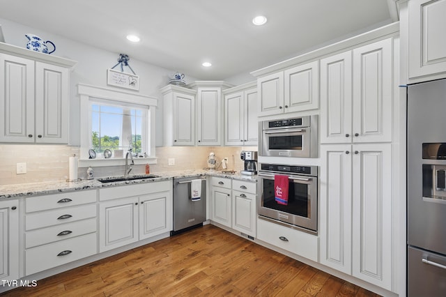 313 Treadway Trl, Jonesborough, TN 37659 - kitchen with appliances with stainless steel finishes, white cabinets, decorative backsplash, light wood-style flooring, and light stone counters