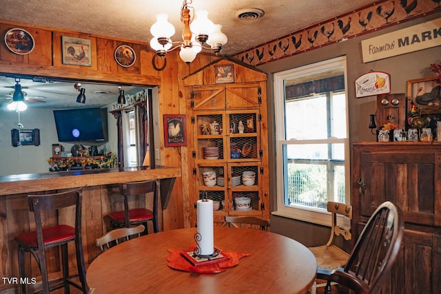 3504 James Phillips Way, Sevierville, TN 37876 - dining area featuring a chandelier, a textured ceiling, a ceiling fan, and wood walls